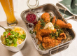 Backhendl mit Beilagen und Bier, serviert im traditionell gestalteten Restaurant.