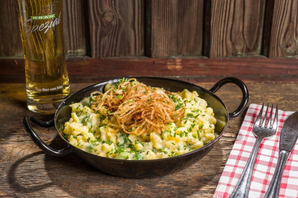 Käsespätzle mit Rösti-Zwiebeln und Bier im Tiroler Restaurant.
