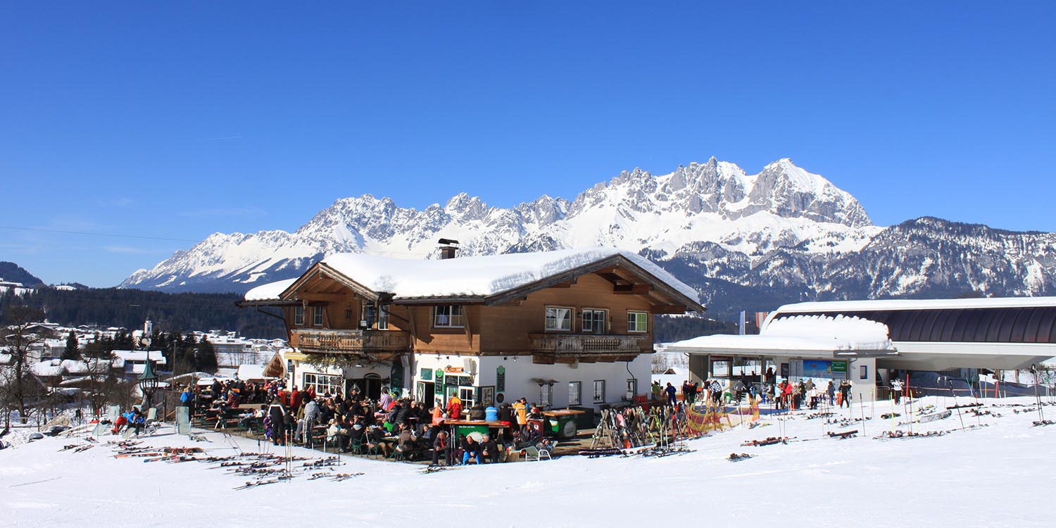 Refuge de ski s'Liftradl avec des clients, entouré par les Alpes enneigées du Tyrol.