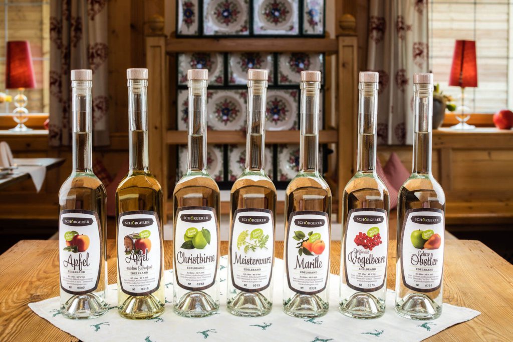 Hausgemachte Obstbrände in dekorativen Flaschen, präsentiert auf einem Tisch im Hotel Penzinghof.