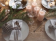 Tavola apparecchiata a festa con candele, piatti decorati e addobbi naturali per l'Avvento.