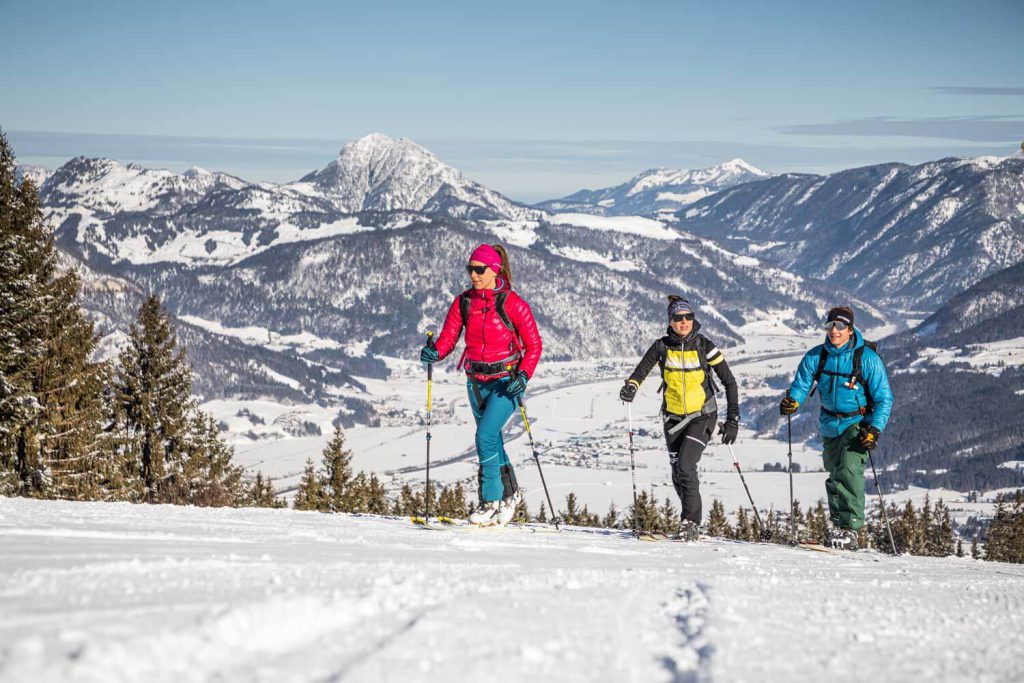 Les amateurs de sports d'hiver se promènent dans le paysage enneigé du Tyrol avec les montagnes en arrière-plan.