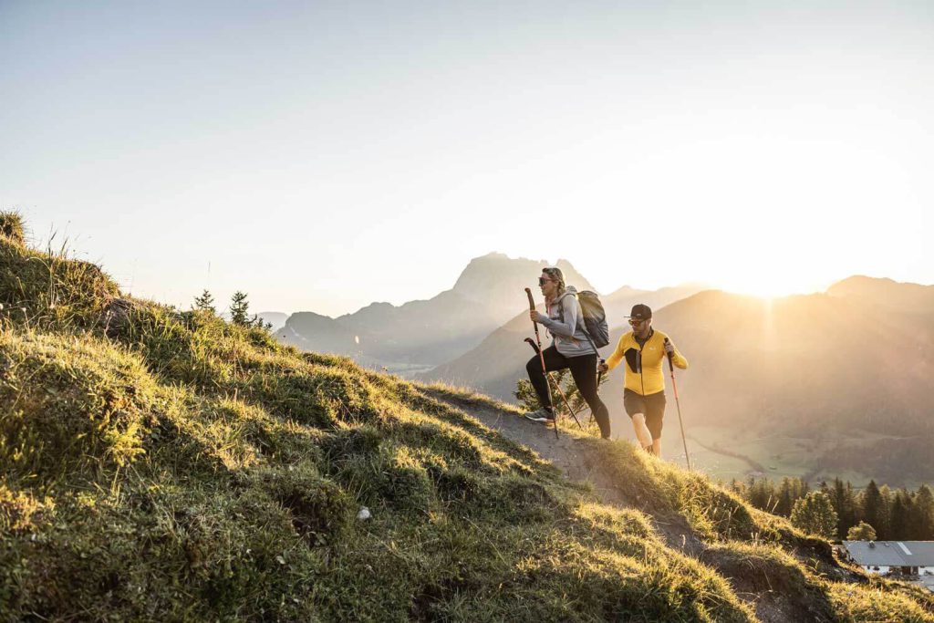Two hikers enjoy the alpine landscape in the Tyrolean mountains at sunset.
