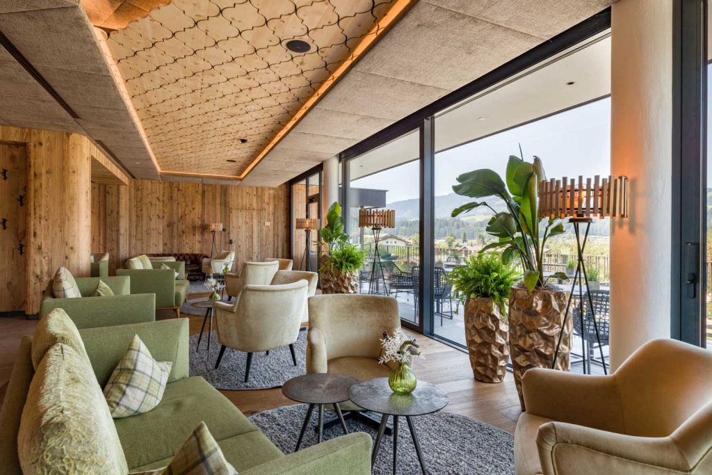 Elegante Lounge im Hotel Penzinghof mit gemütlichen Sitzen und Panoramafenstern zu den Alpen.