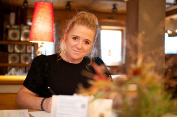 Donna scrive in un'accogliente area dell'hotel con luce calda e sfondo decorativo.