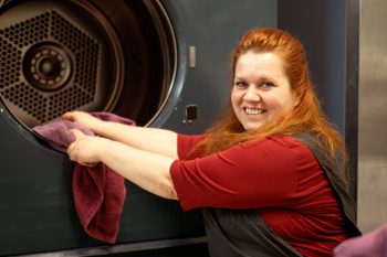 Addetta mentre cambia la biancheria dell'hotel, sorride gentilmente.